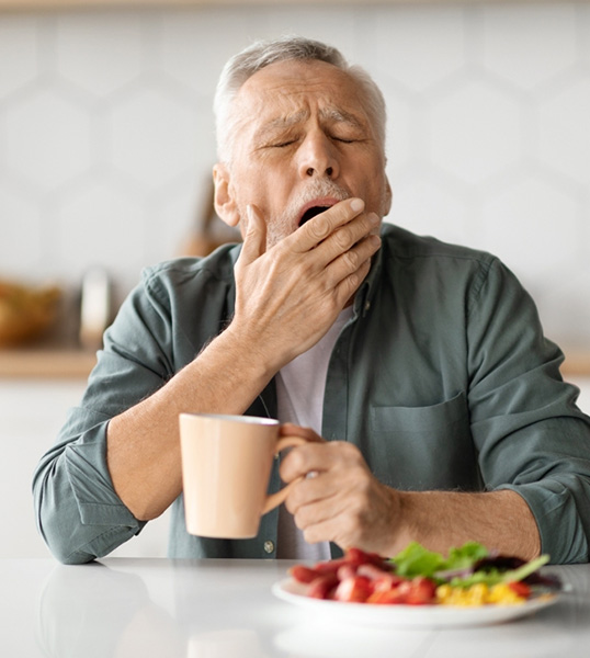 Man yawning while eating breakfast 