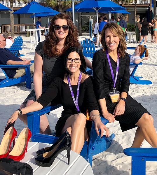 Three Scottsdale sleep apnea team members in black dresses sitting in wooden chairs on beach
